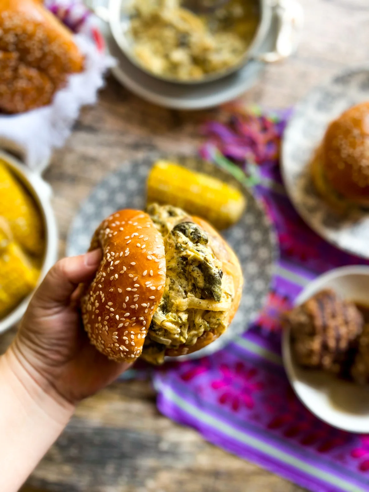 a hand holding a burger with cheesy roasted poblano peppers